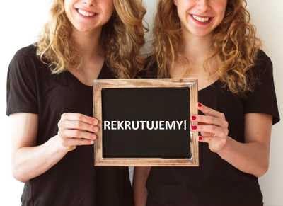 Dwie uśmiechnięte kobiety trzymające tabliczkę z napisem 